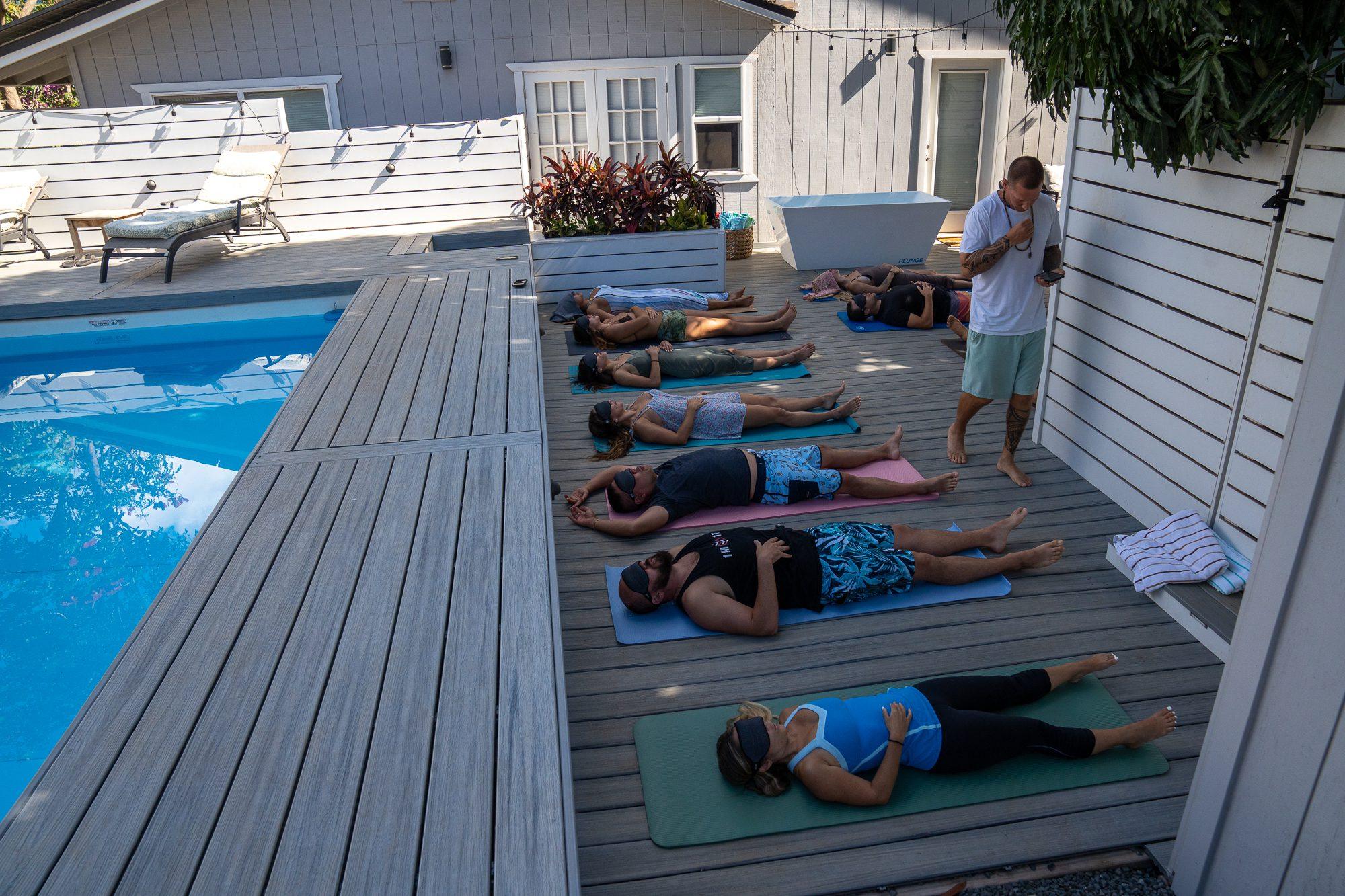 Group practicing breathwork by the pool on the Maui deck