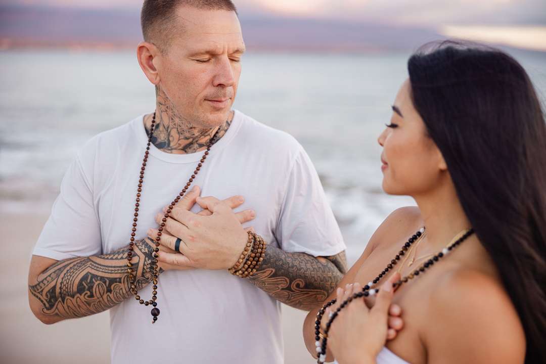 TNT and Paulina practicing breathwork at sunset on a Maui beach